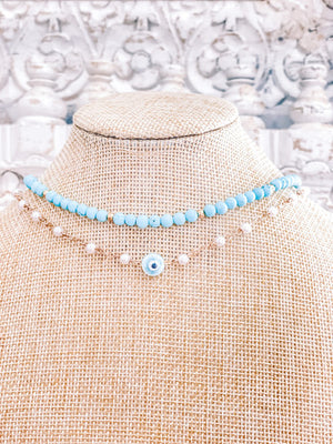turquoise necklace beads paired with a second necklace made of faux pearls and gold plated chain with a blue evil eye charm