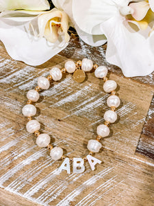 baroque pearl bracelet with gold plated beads separating and pearl white initial letters spelling out aba